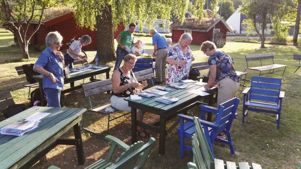 Styrelsen står vid bord utomhus och fixar med medlemstidningen