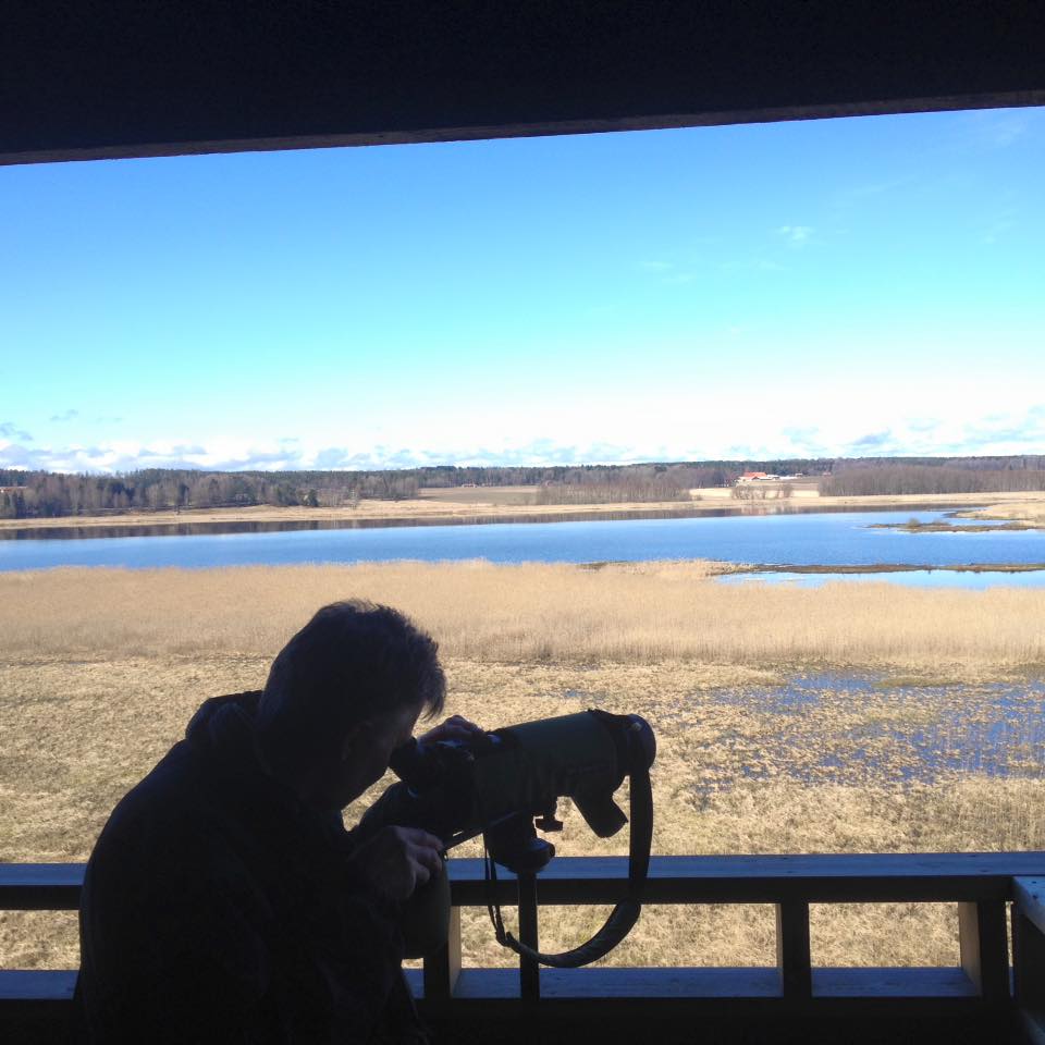 siluett av fotograf som fotar utsikten över sjön från fågeltornet