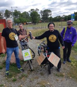 Fyra personer samlas runt cyklar, Barbro lämnar över budkaveln till Jan